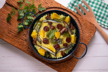 Migas with chorizo, sardines, bacon and green peppers cooked in a black paella. Typical Spanish tapa recipe.