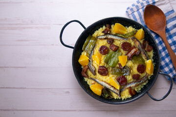 Migas with chorizo, sardines, bacon and green peppers cooked in a black paella. Typical Spanish tapa recipe.