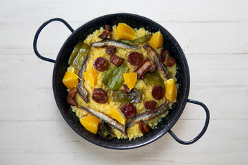 Migas with chorizo, sardines, bacon and green peppers cooked in a black paella. Typical Spanish tapa recipe.