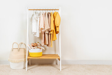 Clothing Rack with children's autumn outfit and Storage Baskets. Yellow, beige, white jacket, dress...
