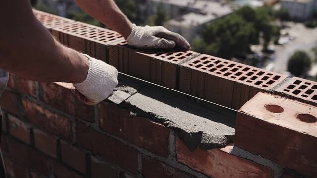 bricklayer lays red brick, masonry wall
