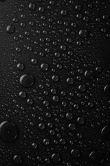 Water. Water drops on a black textured surface. Macro. Vertical image.