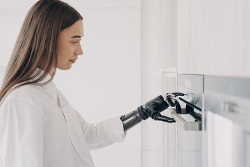 Disabled girl presses button on oven by finger of bionic prosthetic arm. High tech prosthesis ad