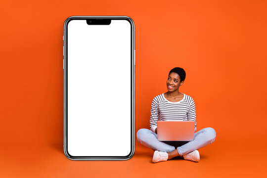 Portrait of attractive cheerful girl using laptop copy blank space idea isolated over vibrant orange color background