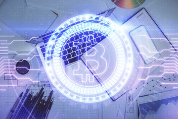 Blockchain theme hologram drawings over computer on the desktop background. Top view. Multi exposure. Concept of cryptoeconomy.