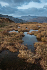 Majestic landscape image of stunning Autumn sunset light across Langdale Pikes looking from Holme Fell in Lake District