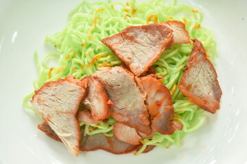 dry Chinese jade egg noodles topping slice barbecue pork on plate with sweet red gravy sauce