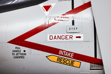 Danger aircraft jet ejector seat rescue and intake signs on side of modern military airforce plane.