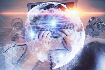 Double exposure of man's hands typing over computer keyboard and business theme hologram drawing. Top view. Financial markets concept.