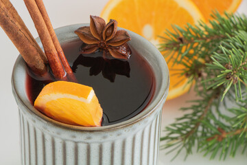 Christmas mulled wine. Punch, grog. The drink is decorated with an orange slice, anise and cinnamon.
Next to him are oranges and spruce branches. Close-up, top view. Composition on a light background.