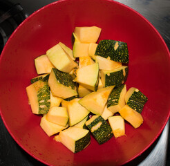 chopped garden fresh yellow pumpkin with skin in red bowl.