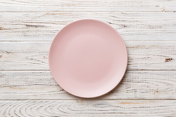 Top view of empty pink plate on wooden background. Empty space for your design