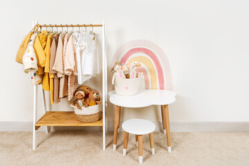 Children's room with Montessori Clothing Rack, white table and Storage Baskets with toys. Dress,...