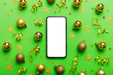 Christmas online shopping from home phone with blank white display top view. smart mobile with copy space on colored background with Christmas decorations balls,. Winter holidays sales background