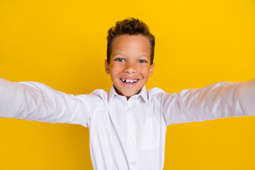 Photo of cheerful attractive boy schoolkid blogger dressed white stylish outfit make photo shooting isolated on yellow color background