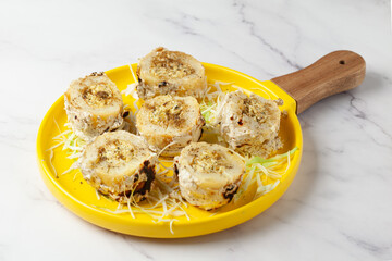 Close-up of Baked stuffed potato with cheese and vegetable garnished with ginger and cabbage julienne  over white granite background.
