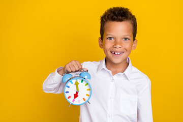 Photo of cheerful person beaming smile arm hold showing clock isolated on yellow color background