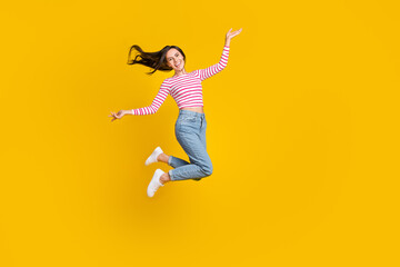 Fototapeta na wymiar Full length photo of gorgeous funky lovely girl wear striped long sleeve denim jeans jumping flying isolated on yellow color background