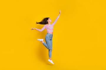 Full length photo of nice cheerful carefree girl dressed striped long sleeve jeans jumping flying isolated on yellow color background - obrazy, fototapety, plakaty