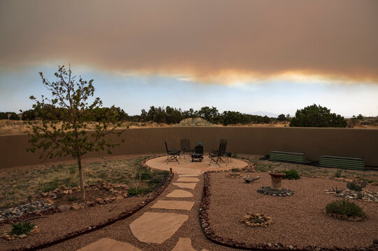 Usa, New Mexico, Santa Fe, Garden in desert landscape with wildfire smoke clouds at sunset