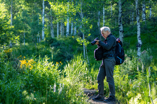 Senior man taking photographs while hiking