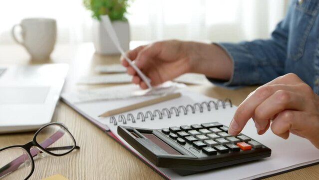 A young woman checks bills, a cash receipt for purchases and calculates budget expenses. Family finance concept.