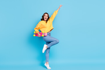 Obraz na płótnie Canvas Full length photo of funky cool lady wear yellow sweater having fun holding longboard empty space isolated blue color background