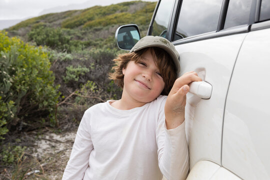 Portrait of boy (8-9) standing by car in Walker Bay Nature Reserve