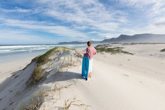 South Africa, Western Cape, Hermanus, Teenage girl (16-17) preparing to surf down sand dunes in Walker Bay Nature Reserve