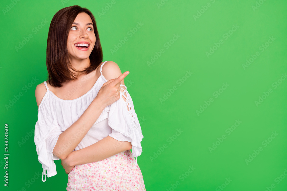 Wall mural portrait of cheerful lovely person beaming smile look direct finger empty space isolated on green co