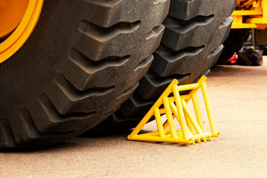Yellow chock, wheel chock, under the wheel of a mining truck. Brake shoe. Security engineering.