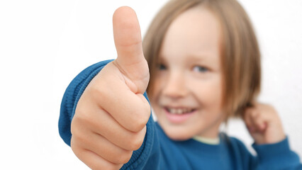 Close-up of a happy smiling boy's hand showing thumb up
