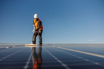 A worker is cleaning solar panels from dust.