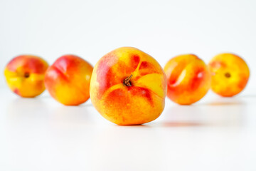 Ripe nectarine in center on white, several nectarines lined up behind it in a blur, space for text at top and bottom of photo, close-up, at eye level