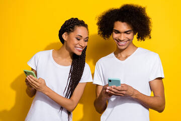 Portrait of cheerful attractive lady look interested handsome guy telephone texting isolated on yellow color background