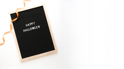 Lettering Happy Halloween in a wooden frame and an orange ribbon on a white background