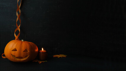 Pumpkin lantern, burning candle, orange ribbon on a black background with a copy space