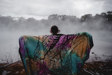 young man from behind covered with a colorful blanket in lake rotorua