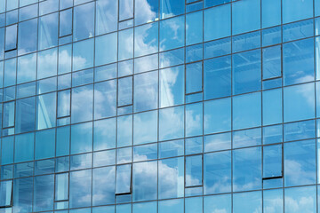 Naklejka na ściany i meble Skyscraper glass on a sunny day. Reflection of the blue sky from the windows of a skyscraper.