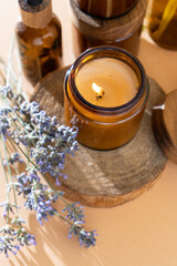 Fototapeta na wymiar Soy candles in a glass jar. Aromatherapy. Burning candle and lavender. Wooden lid for jars. Beige background. Comfort and relaxation. Handmade. Home decor.