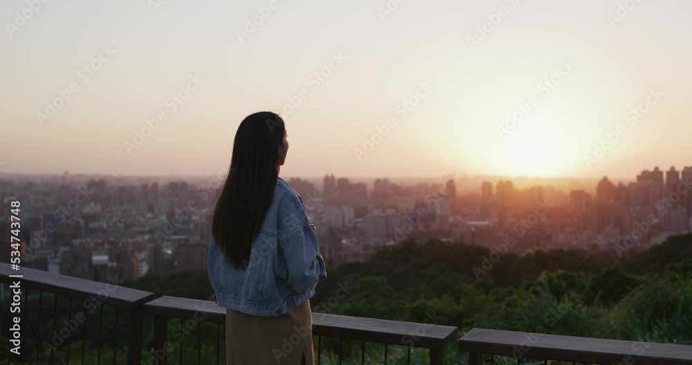 Wall mural woman look at the city view under sunset