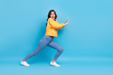 Fototapeta na wymiar Full length photo of impressed excited lady wear yellow sweater pulling big empty space isolated blue color background