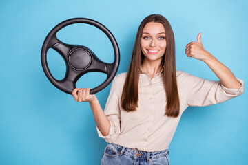 Photo of cute young lady hold wheel thumb up wear casual cloth isolated on blue color background