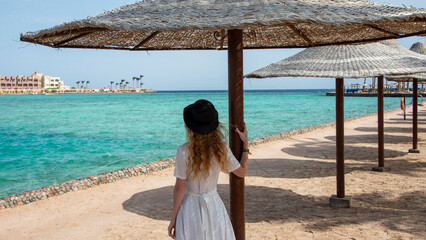 Girl near the turquoise sea with a beach umbrella