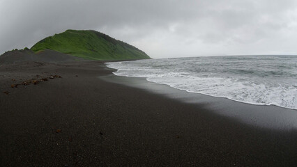 view of the hill, black sand and the sea