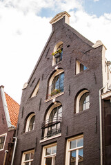 Fachada t&iacute;pica de ladrillo negro con ventanas de arco de media punta de edificio de amsterdam, pa&iacute;ses bajos, holanda