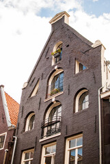 Fototapeta na wymiar Fachada típica de ladrillo negro con ventanas de arco de media punta de edificio de amsterdam, países bajos, holanda