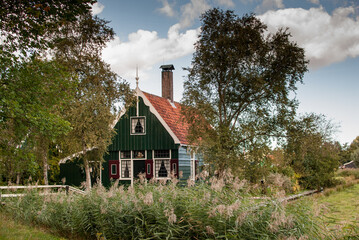 bonita casa de campo verde con tejado de tejas naranjas en el campo rodeada de árboles en el pueblo  De Zaanse Schans en holanda, países bajos