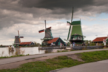 Molino de viento tradicional en pueblo turístico holandés, junto al rió Zaan en países bajos,...