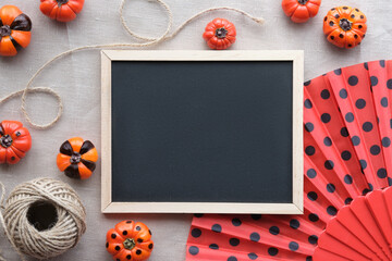 Cute Autumn decor, blackboard with copy-space. Orange mini pumpkins painted black and fan with...
